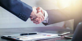 twee mensen in pak schudden elkaar de hand over een contract